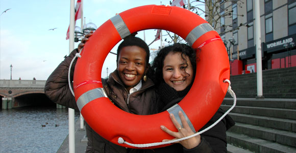 young adults of dark and white skin color are looking happily through a life ring, location is Binnenalster