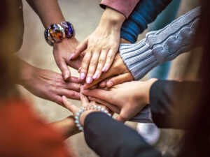 Hände mehrerer Personen übereinander gelegt