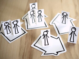 stilisierte Papierfiguren auf Häusern stehend