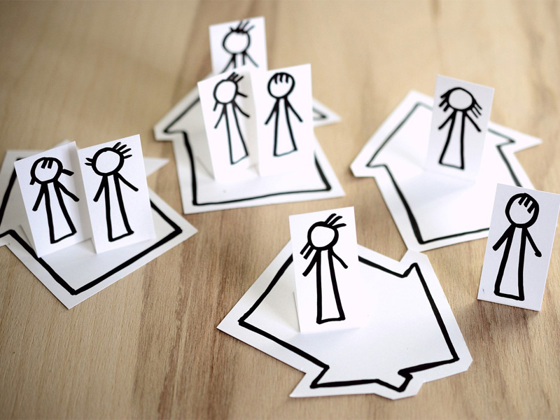 stilisierte Papierfiguren auf Häusern stehend