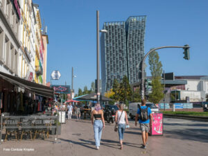 Reeperbahn mit Passant:innen im Sommer, Hintergrund mit tanzenden Türmen
