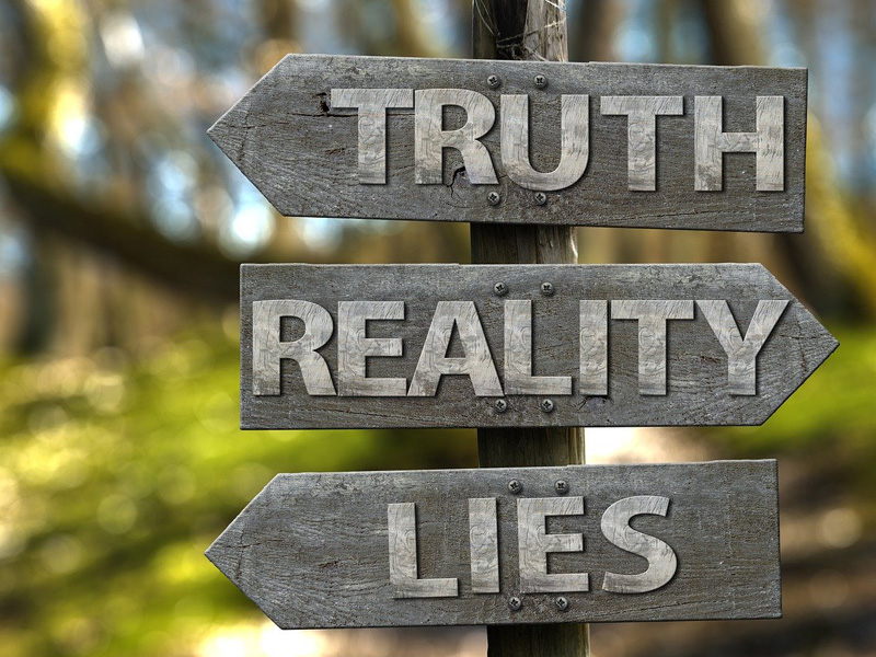 dreiteiliger Wegweiser mit Aufschrift Wahrheit, Realität, Lüge