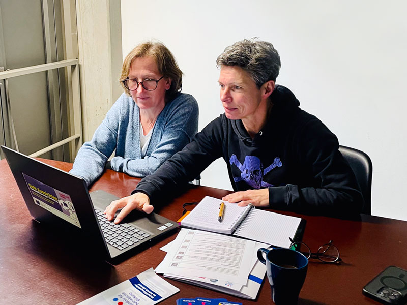 zwei Frauen sitzen am Tisch vor einem Notebook