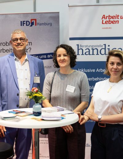 Gruppenbild mit 5 Personen vor Rollup am Messestand