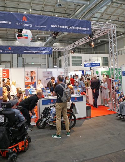 Personen mit und ohne Rollstuhl am Messestand vom Integrationsamt Hamburg